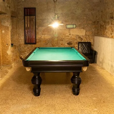 Sala de bilhar com paredes em pedra à vista, na cave da Casinha